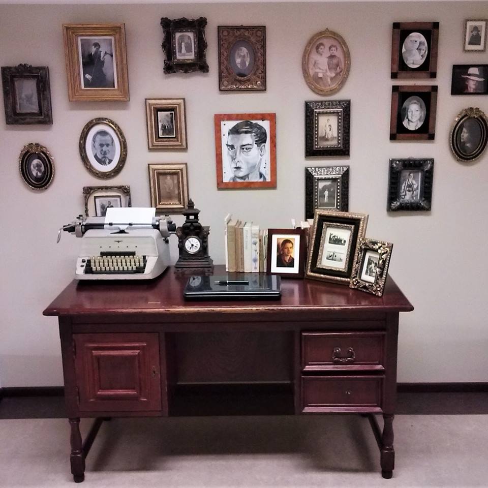 Zdjęcie biurka, przy którym pracował Włodzimierz Odojewski, z maszyną do pisania, książkami, zabytkowym zegarem i ramkami ze zdjęciami.